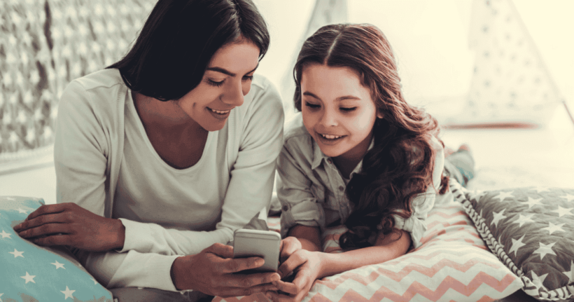 A mum uses a smartphone with her daughter.