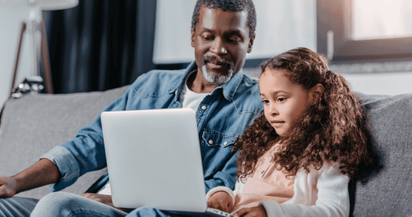 A dad uses a laptop with his daughter.