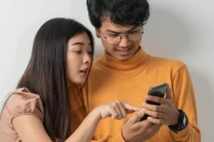 Two teens look at a smartphone.