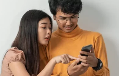 Two teens look at a smartphone.