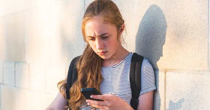 A girl frowns at her phone.