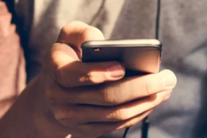 A close up image of a hand holding a smartphone, possibly scrolling social media.