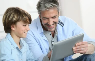 A dad uses a tablet with his son.